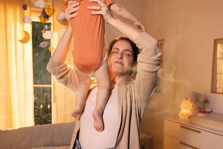 Une femme soulève son bébé pour vérifier sa couche et est immédiatement dégoûtée par l'odeur.